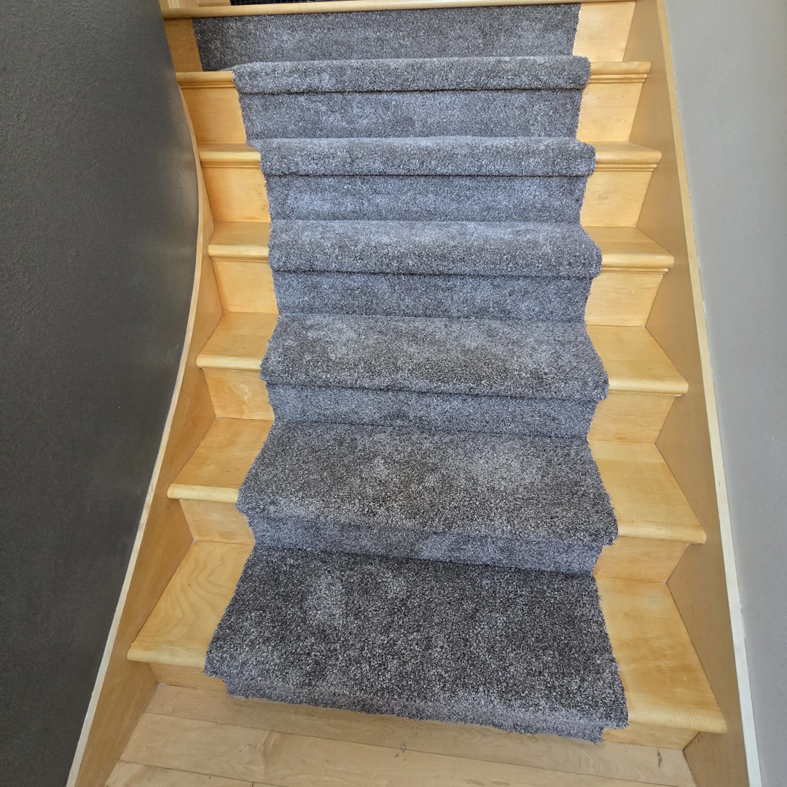 Dark gray carpet runners professionally installed on a wooden staircase by L.A. Floors in Madison, WI.
