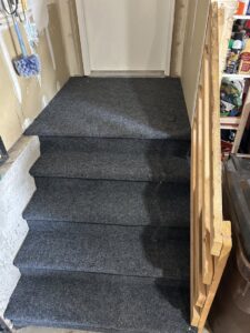 Newly installed carpet on stairs leading to a door, a service provided by Wam Bam Handyman LLC in Colorado Springs, CO