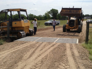 Workers overseeing cattle guard installation and dirt road work by Daniel Dean Land Clearing & Dirt Work in Houston, TX.