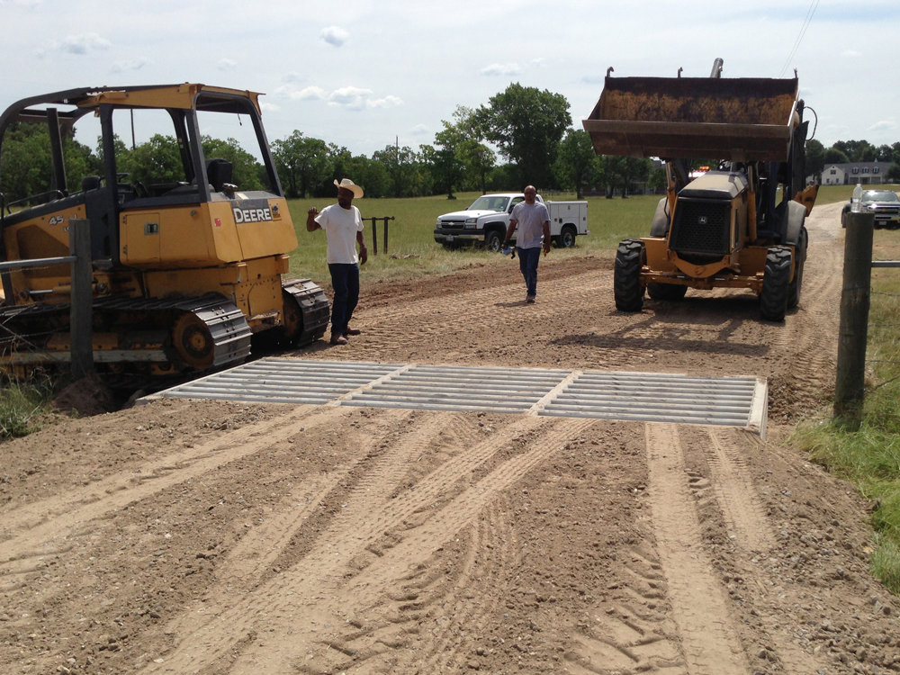 Workers overseeing cattle guard installation and dirt road work by Daniel Dean Land Clearing & Dirt Work in Houston, TX.