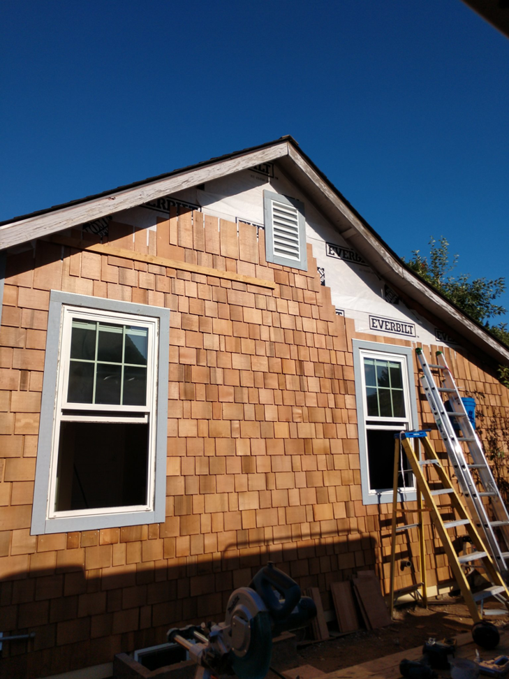 Cedar shake siding installation on a house exterior with new windows by Hessel Carpentry in Portland, OR.
