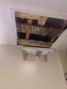 A large hole in a ceiling with exposed framing, indicating a repair job by Drywall Paint Plus in Worcester, MA.
