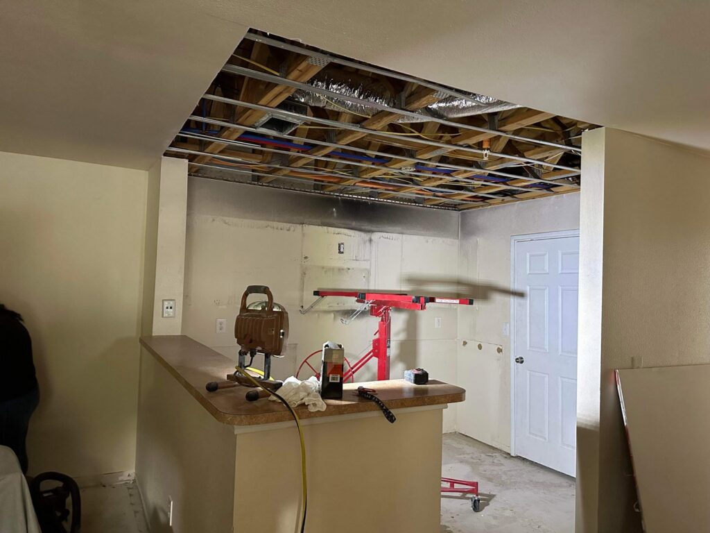 A ceiling under construction, showing exposed framing, insulation, and a drywall lift in use by SMM Services LLC in Gulfport, MS.