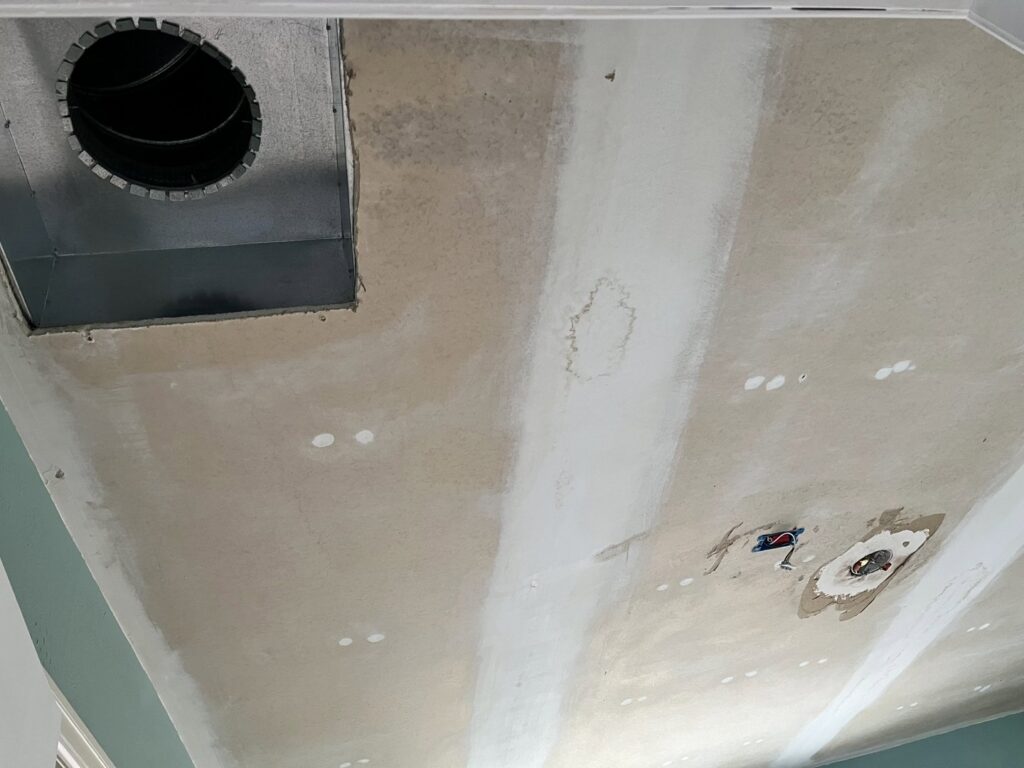 A ceiling with newly installed and taped drywall, including a vent opening, by Asbestos Abatement, Inc in Englewood, CO.