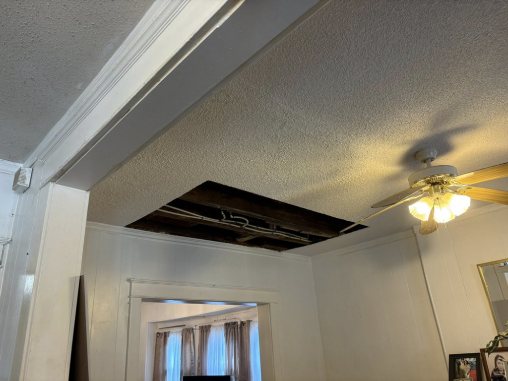 A ceiling with a section cut out, exposing pipes and beams for drywall repair by Gama Home & Lawn Services LLC in Kansas City, MO.