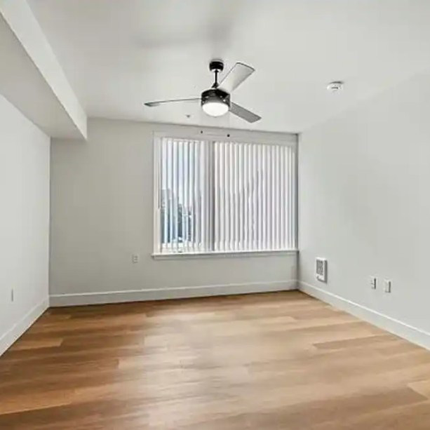 An empty room showcasing a newly installed ceiling fan and vertical window blinds by IM Construction LLC in Mount Vernon, WA.