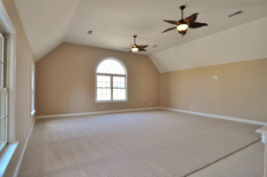 A spacious room with new carpet, light beige walls, and two ceiling fans installed by Nixon Construction in Nashville, TN.