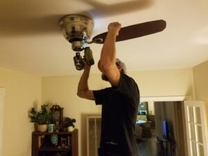 A contractor installing a new ceiling fan in a home by Red Gator Maintenance in Fresno, CA.