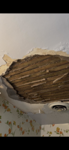 A large hole in a ceiling exposing wooden lath, indicating a plaster repair job by Eric Aulbach Plastering in Saint Louis, MO.
