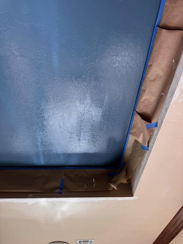 Ceiling painting in progress with masking paper and blue tape for protection, by Sanders Construction & Handyman Services, LLC in Oklahoma City, OK.