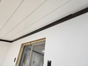 Handyman Dan INC installing ceiling paneling and trim around a window in Fremont, NE.