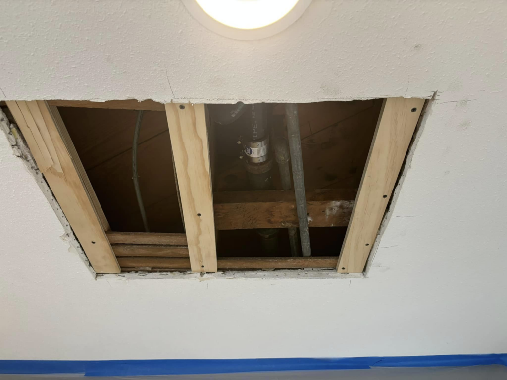 Ceiling repair or access hole exposing pipes and wiring, a service by Considerate Repair in Walla Walla, WA.