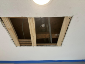 Ceiling repair or access hole exposing pipes and wiring, a service by Considerate Repair in Walla Walla, WA.