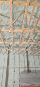Close-up of spray foam insulation on a ceiling and upper wall by Tumbarello Insulation in Peyton, CO.