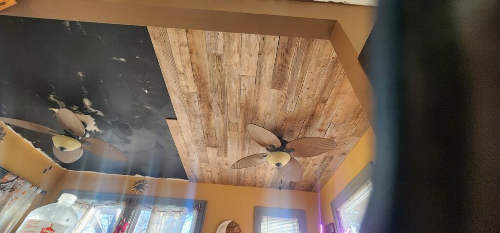 A ceiling with new wooden planks installed, showcasing a renovation project by SAM'S Handywork LLC in Independence, IA.