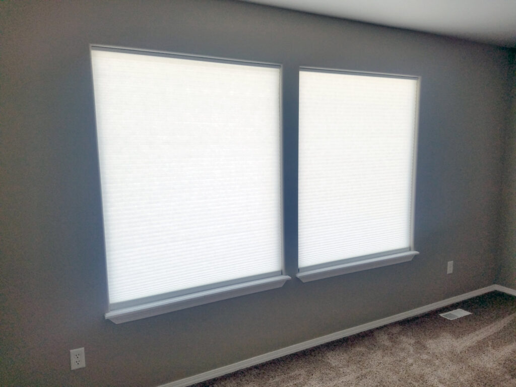 Newly installed white cellular blinds on two windows, a service provided by Boise Handyman & Remodel in Boise, ID.