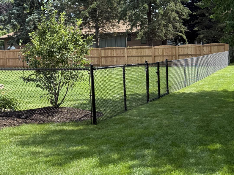 A long chain-link fence and a wooden privacy fence installed in a backyard by Fence World Of Janesville, Janesville, WI.