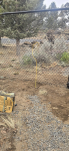 Chain-link fence installation in progress with a bag of concrete mix and gravel by Michel's Fencing in Bend, OR
