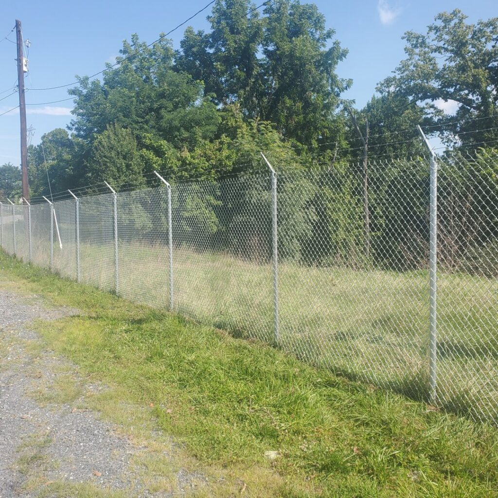 A chain-link fence with barbed wire installed along a grassy area by Quality Fence & Deck Co. in Frederick, MD.