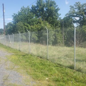 A chain-link fence with barbed wire installed along a grassy area by Quality Fence & Deck Co. in Frederick, MD.