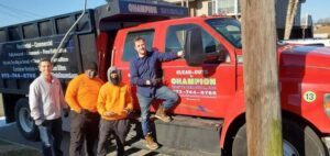 The Champion Waste Removal, Inc. team standing proudly next to their red dump truck in Orange, NJ.