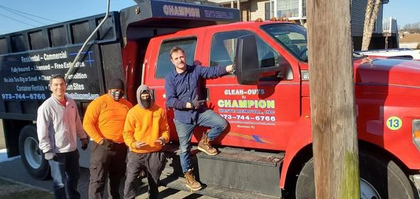 The Champion Waste Removal, Inc. team standing proudly next to their red dump truck in Orange, NJ.