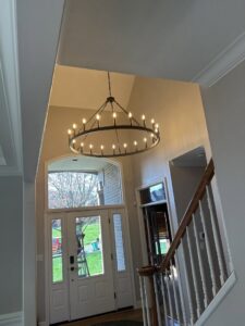 A newly installed large chandelier in a high-ceiling entryway by Mr. Handyman of Northern Pittsburgh, PA.