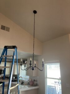 A new chandelier installed in a room with a high ceiling, with a ladder nearby, by Absolute Integrity Handyman Services Inc in Fresno, CA.