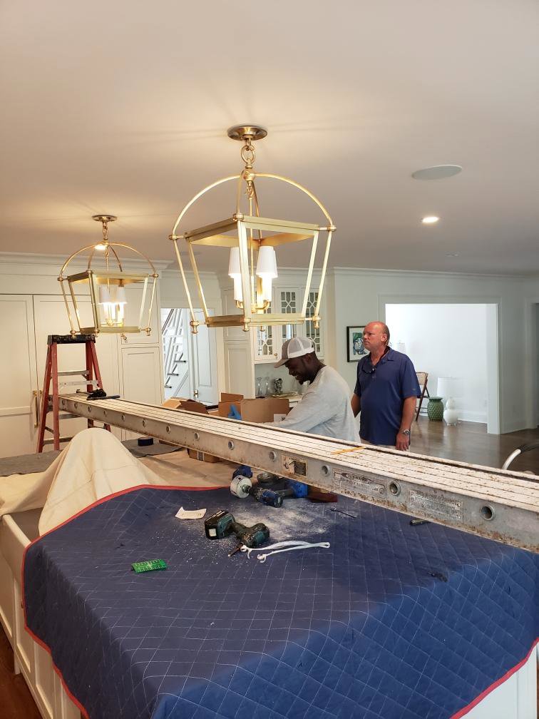 Two technicians providing chandelier installation service by Carolina Custom Electric in Mount Pleasant, SC.