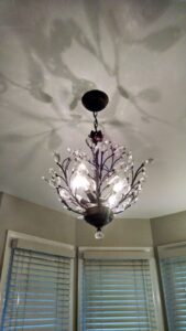 A newly installed chandelier light fixture casting decorative shadows on the ceiling by Unique Construction Services in Knoxville, TN