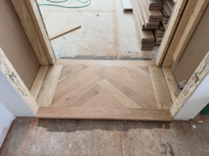 Hardwood floor installation in progress, showing a chevron pattern by Heritage Floors of Hanover LLC in Mechanicsville, VA.