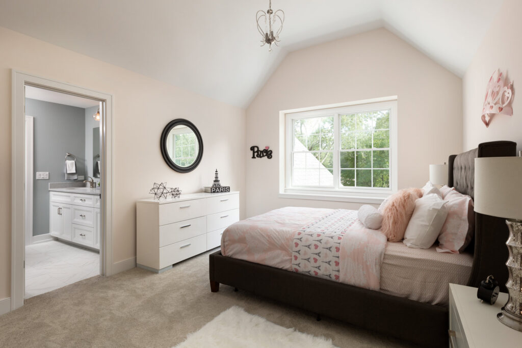 A child's bedroom with pink bedding and a connected bathroom, part of a home built by Autumn Homes in Naperville, IL.