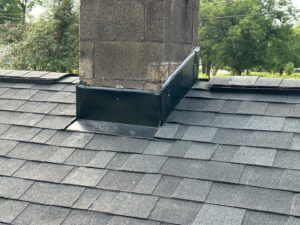 Detailed view of chimney flashing expertly installed on a shingle roof by Roofing Experts Care in Charlotte, NC.