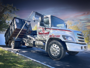 A Christensen Recycling roll-off truck with a dumpster in a residential driveway in Sayreville, NJ.