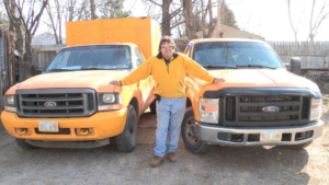 Chuck with the yellow truck standing between two yellow junk removal trucks in Omaha, NE.