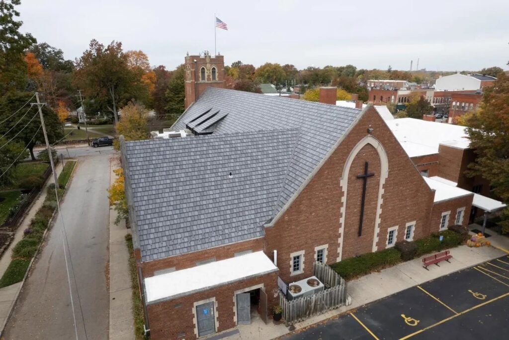An aerial view of a church building featuring a newly installed gray shingle roof by Keep It Simple Construction LLC in Woodburn, IN.