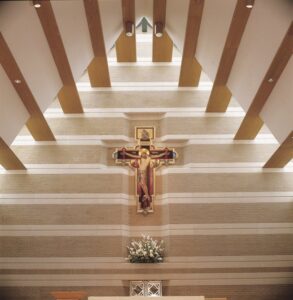 The serene interior of a church with a large crucifix and architectural beams, a project by Dallas Cast Stone in Dallas, TX