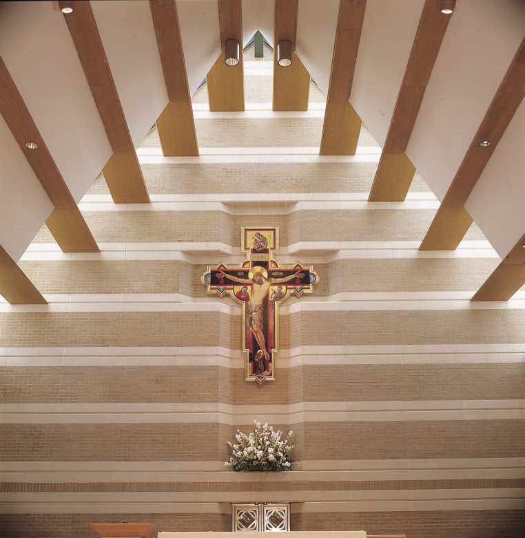 The serene interior of a church with a large crucifix and architectural beams, a project by Dallas Cast Stone in Dallas, TX