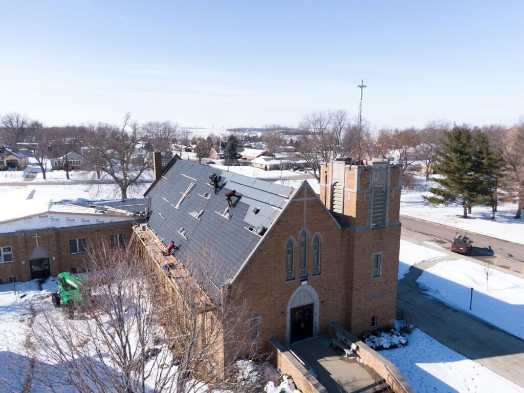 Workers performing a roof replacement on a church in winter by Roof-Rite Solutions, LLC in Council Bluffs, IA