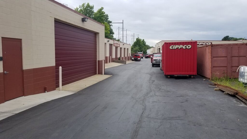 An outdoor view of Cippco Inc.'s company yard with branded containers and trucks, showcasing their general contracting operations in Philadelphia, PA.