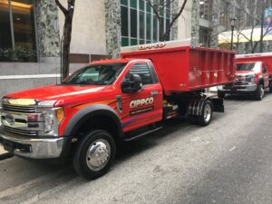 A red Cippco Inc. dump truck parked on a city street, representing general contracting services in Philadelphia, PA.