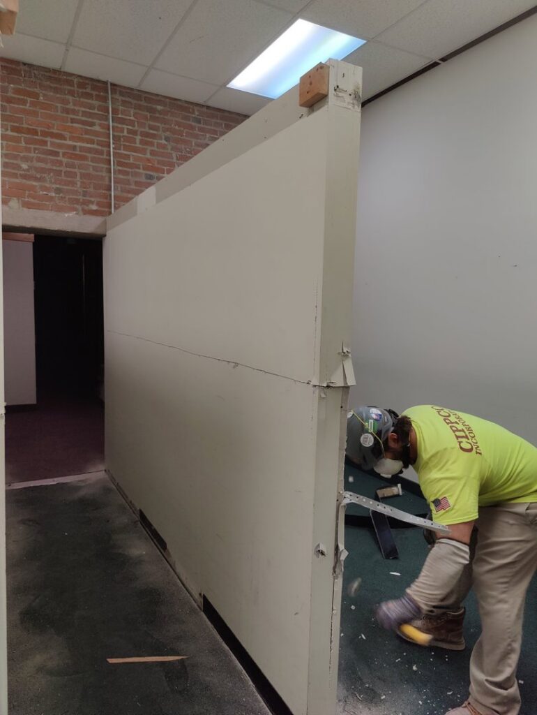 A Cippco Inc. worker wearing safety gear, actively demolishing an interior wall during a general contracting project in Philadelphia, PA.