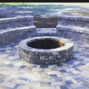 A circular paver patio with a central fire pit and stone seating under construction by Keystone Design in Tallahassee, FL.