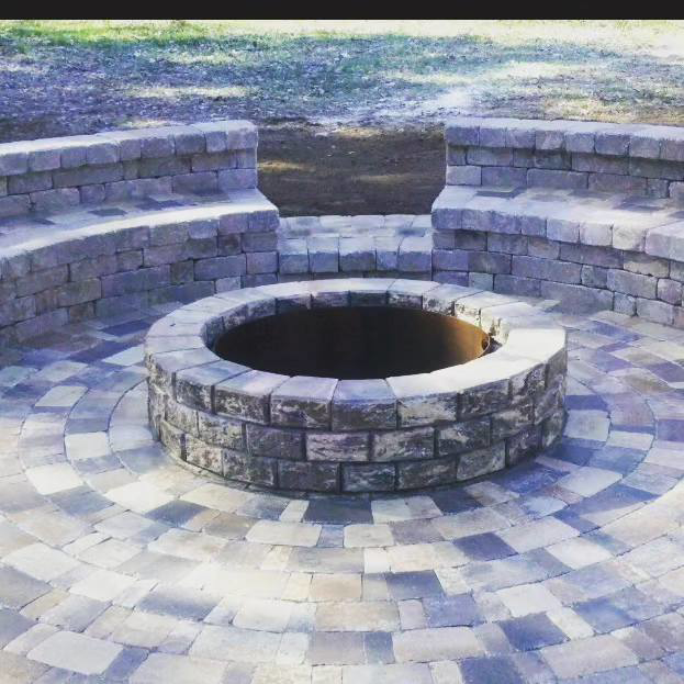 A circular paver patio with a central fire pit and stone seating under construction by Keystone Design in Tallahassee, FL.