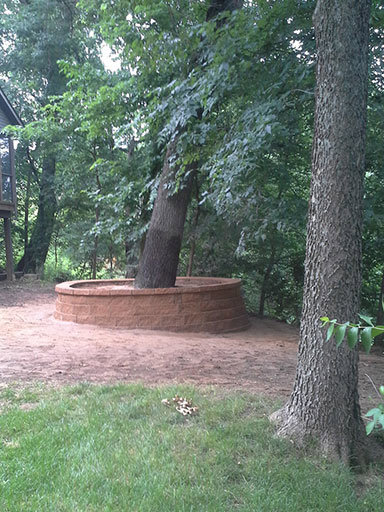 A newly constructed circular retaining wall built around a large tree by Green Way Landscaping LLC in Iowa City, IA.