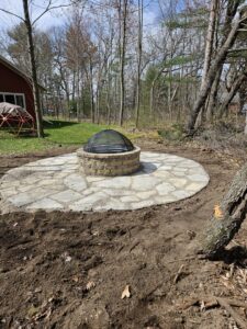 A circular stone fire pit area with flagstone pavers installed by Wildflower Landscapers LLC in Larsen, WI