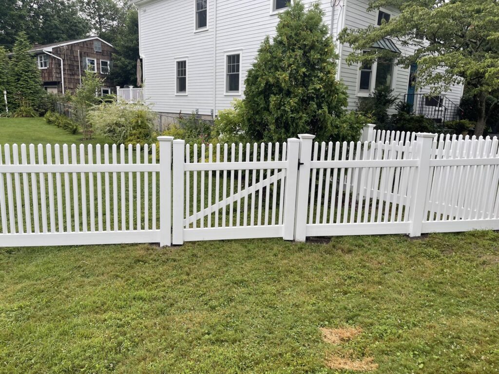 A classic white picket fence with a sturdy gate, professionally installed by Fence Factory Inc in Stamford, CT