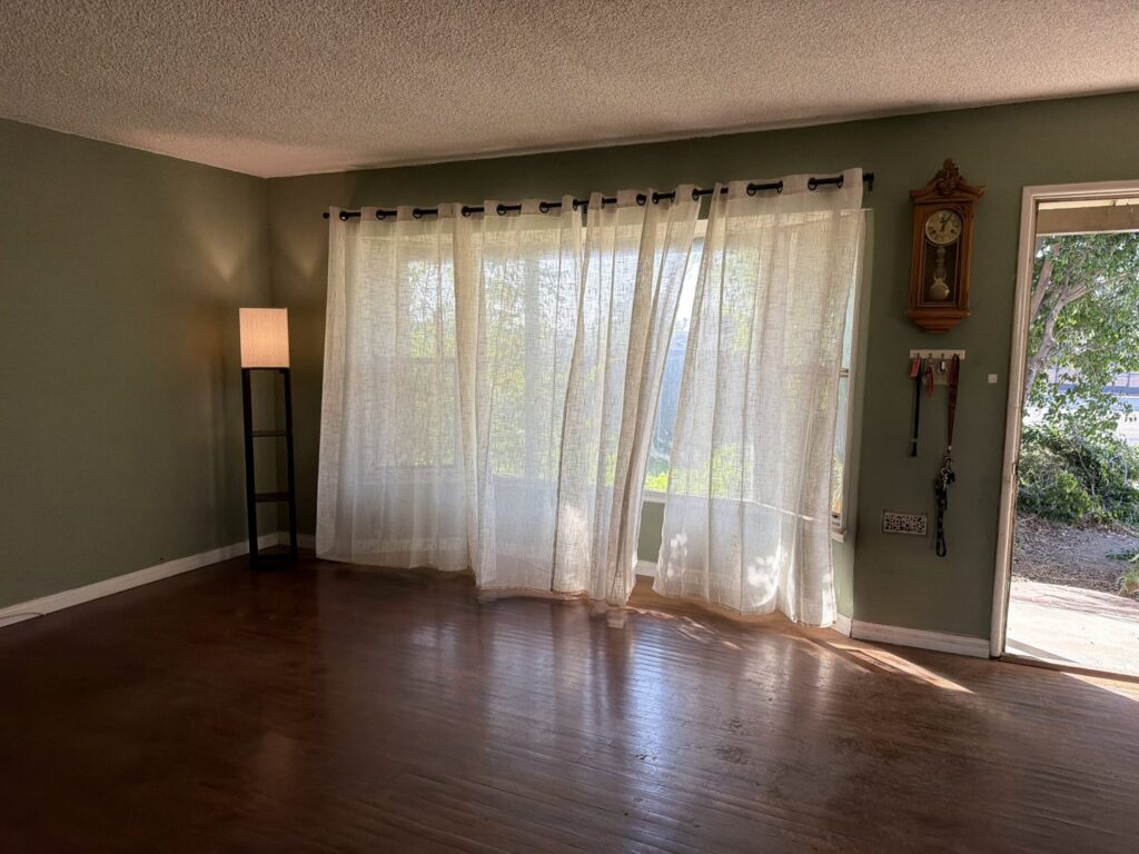 A clean, empty room with hardwood floors and curtains after a junk removal service by Larry The Rubbish Man in Los Angeles, CA.