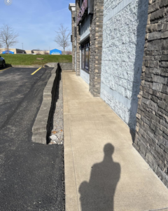 A clean exterior sidewalk next to a stone building, showing results of power washing by A 2 Z Home Services - Fairmont WV.
