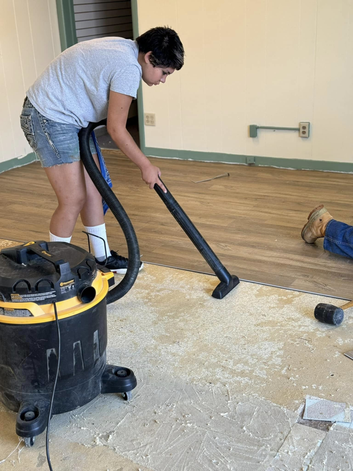 A person vacuuming the subfloor during a renovation project by Wheeler's Handyman Services in Vermillion, SD